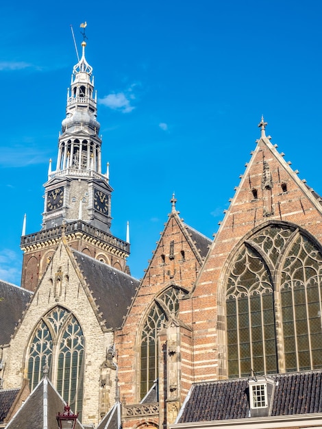 Facciata anteriore e torre dell'orologio della Chiesa Vecchia nel quartiere a luci rosse di Amsterdam sotto il cielo di luce naturale serale