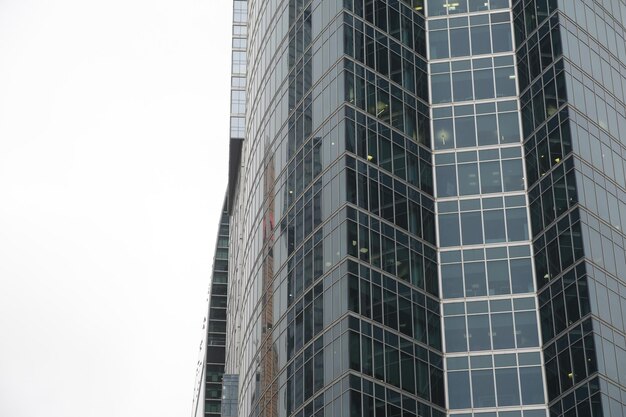 Facciata del moderno grattacielo con pareti di vetro Dal basso del moderno grattacielo alto con pareti di vetro contro il cielo nuvoloso nel centro cittadino