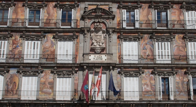 Facciata di un edificio storico con bandiere istituzionali nella piazza principale di Madrid Spagna