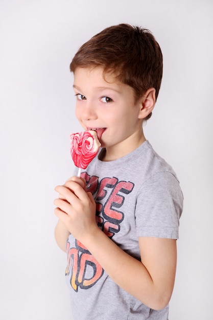 Faccina felice di un ragazzo che lecca caramelle lecca-lecca