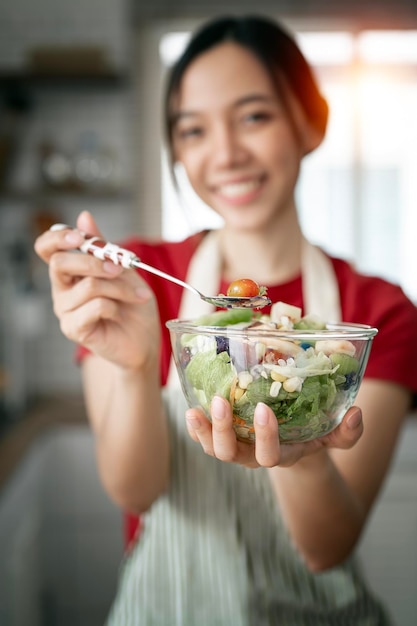 Faccina felice donna che tiene insalatiera in piedi in cucina camera stile di vita sano cibo sano Cucinare a casa preparare il cibo