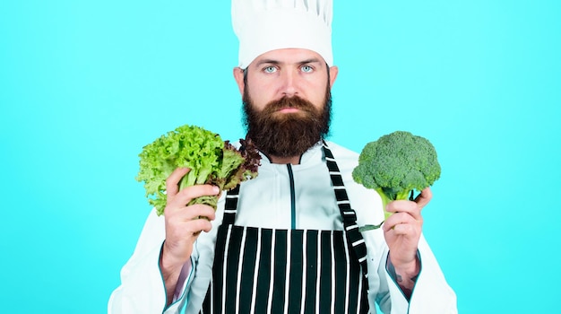 Faccio sempre una scelta salutare Chef professionista in uniforme Dieta con alimenti biologici Verdure fresche uomo serio che cucina in cucina Vitamina uomo usa stoviglie Cibo sano e vegetariano