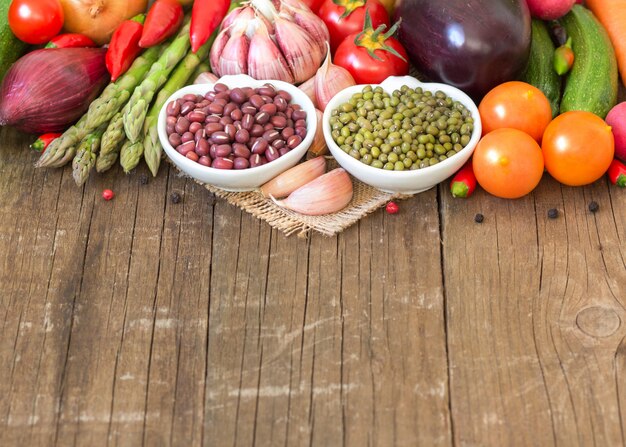 Fagioli azuki e verdi in ciotole e verdure sulla fine di legno su