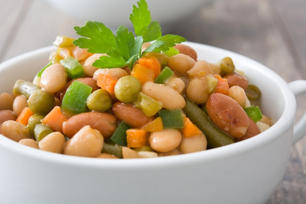 Fagioli bianchi con le verdure in tavola di legno della ciotola