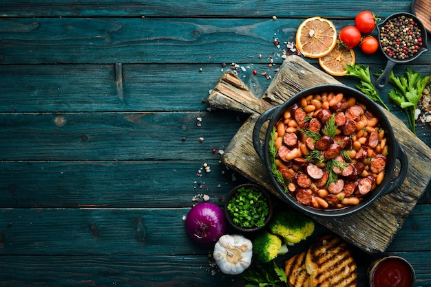 Fagioli con salsicce in salsa di pomodoro su un piatto nero Vista dall'alto Spazio libero per il testo