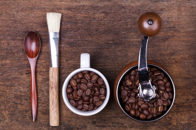 Fagioli e cucchiaio della tazza di caffè sui precedenti di legno marroni