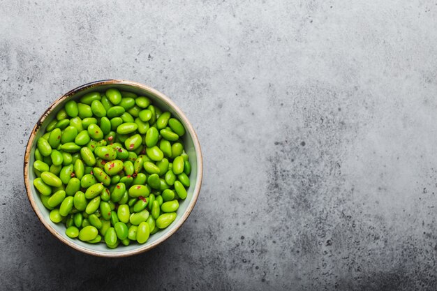 Fagioli edamame verdi maturi freschi senza baccelli in ciotola su fondo di pietra grigia con spazio per testo. Vista dall'alto, primo piano. Spuntino asiatico leggero e sano, buona fonte di proteine per dieta e nutrizione and