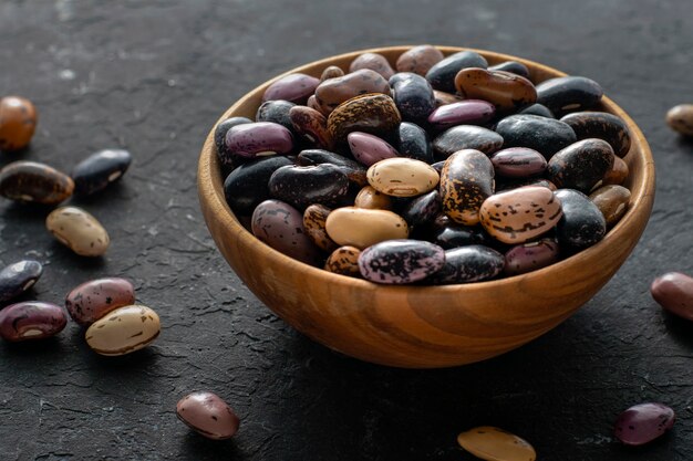 Fagioli in una ciotola di legno su un muro di cemento nero.