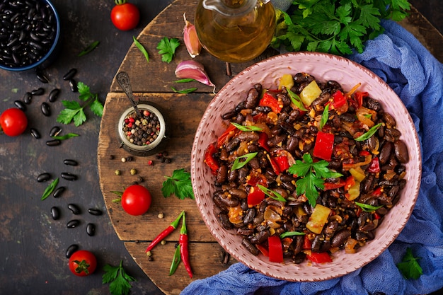 Fagioli neri in umido con peperoni e pomodori con salsa piccante in una ciotola rosa