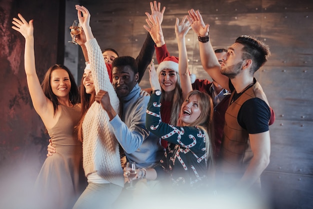 Fai festa con gli amici. Loro amano il Natale. Il gruppo di giovani allegri che trasportano le stelle filante e le scanalature di champagne che ballano nel nuovo anno fanno festa e che sembrano felici. Concetti sullo stile di vita insieme