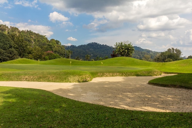 Fairway di un bellissimo campo da golf con bunker di sabbia sotto il drammatico cielo estivo