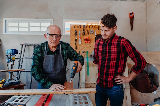 Falegname senior che insegna a un uomo più giovane come lavorare