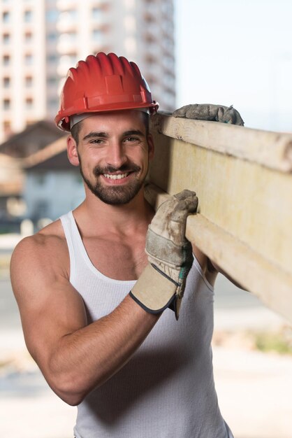 Falegname Sorridente Che Porta Una Grande Tavola Di Legno Sulla Sua Spalla