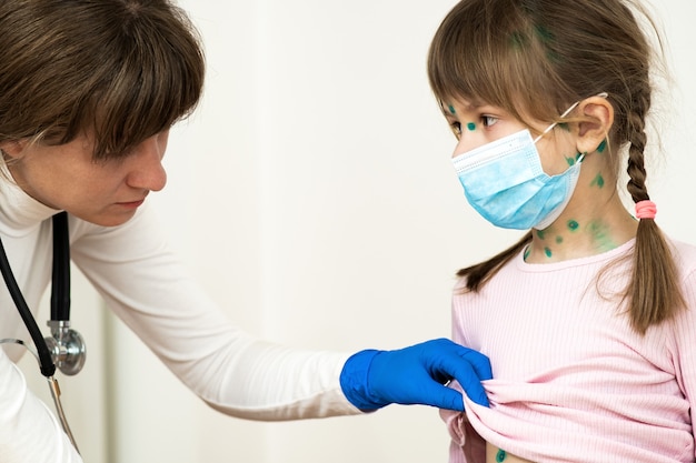 Falsifichi l'esame della ragazza del bambino coperta di eruzioni cutanee verdi sul viso e sullo stomaco malato di varicella, morbillo o virus della rosolia.