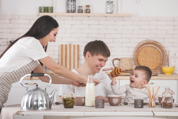 Famiglia adorabile che cucina togrther. Giovane famiglia in cucina a colazione o cena. Mamma, papà e il loro bambino stanno preparando il pasto.