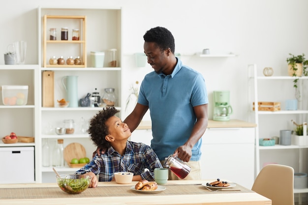 Famiglia africana di due padre e figlio che fanno colazione insieme nella cucina domestica