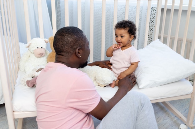 Famiglia afro-americana, papà e figlio che parlano o giocano in camera da letto a casa, padre felice