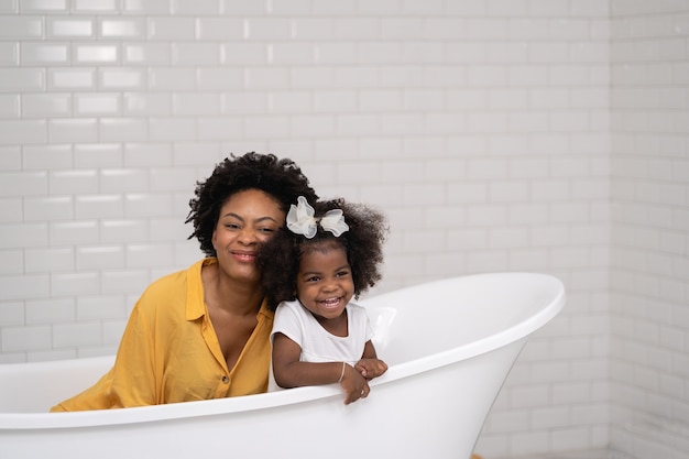 Famiglia afroamericana, madre felice e figlia che si divertono e giocano insieme in bagno