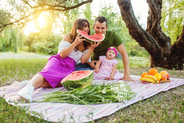 Famiglia al picnic Genitori che mangiano un'anguria Bambina che guarda l'obbiettivo