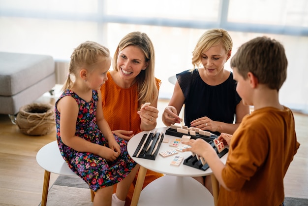 Famiglia al tavolo che gioca a un gioco da tavolo con i bambini. Coppia lesbica, asilo nido, concetto di infanzia.