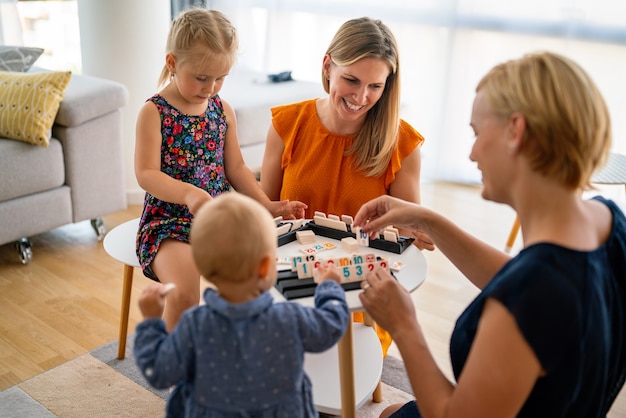 Famiglia al tavolo che gioca a un gioco da tavolo con i bambini. Coppia lesbica, asilo nido, concetto di infanzia.