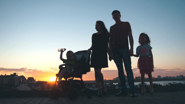 Famiglia al tramonto - padre, madre, figlia e figlio piccolo - silhouette, teleobiettivo