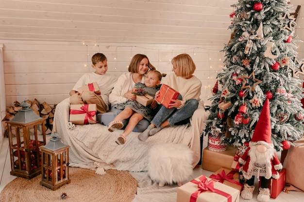 Famiglia alla vigilia di Natale. I bambini aprono i regali. Bambini sotto l'albero di Natale con scatole regalo. Stanza decorata di Capodanno. Serata d'inverno calda e accogliente a casa.