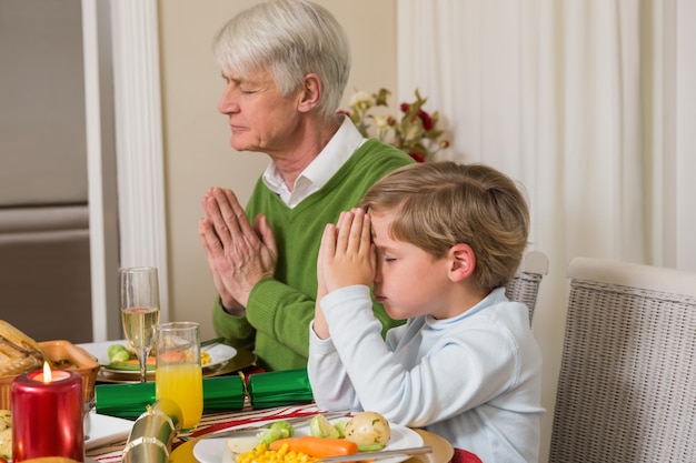 Famiglia allargata che prega prima della cena di Natale