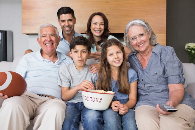 Famiglia allargata guardando la tv sul divano nel soggiorno