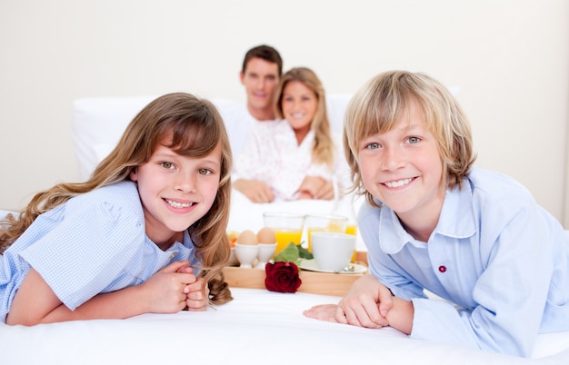 Famiglia allegra facendo colazione seduto sul letto