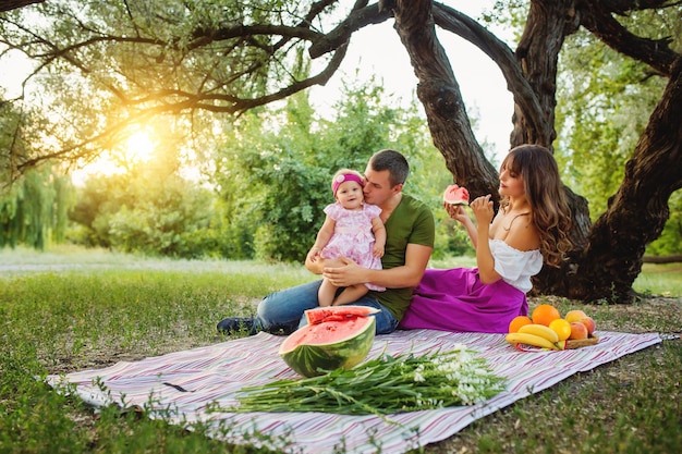 Famiglia allegra seduta sull'erba durante un picnic in un parco