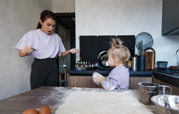 Famiglia amorevole felice che cucina insieme panetteria. Madre e figlia cucinano i biscotti e si divertono in cucina. Cibo fatto in casa e un piccolo aiutante.