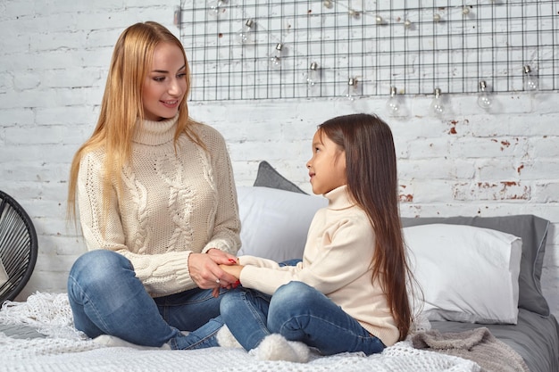 Famiglia amorevole felice. Madre e figlia bambina che giocano e si abbracciano sul letto