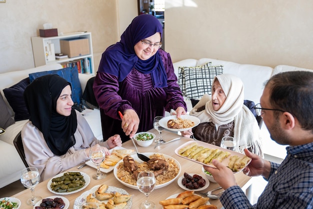 Famiglia araba che cena insieme su un tavolo di legno con padre, madre, nonno, nonna e figlio