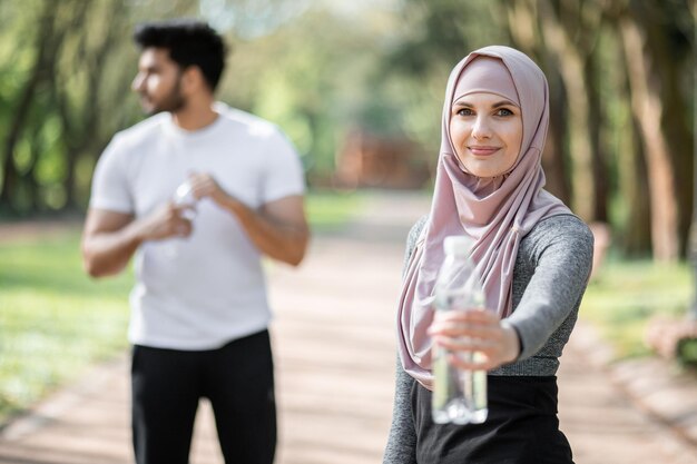 Famiglia araba in posa al parco con acqua di bottiglia