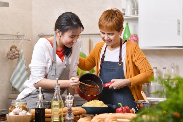 Famiglia asiatica amorosa della madre e della figlia che cucinano nella cucina che produce insieme alimento sano sentirsi divertimento