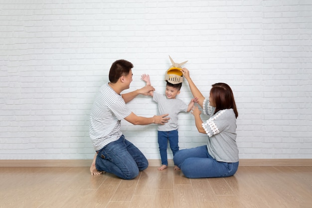 Famiglia asiatica che gioca con il figlio e che sorride mentre trascorrendo tempo libero a casa