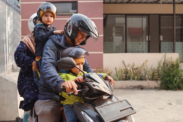 Famiglia asiatica che guida uno scooter in moto insieme in viaggio con i bambini