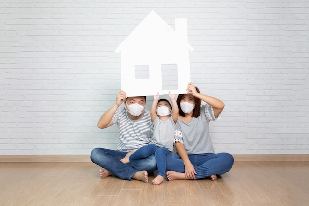 Famiglia asiatica che indossa casa protettiva della carta della tenuta della maschera