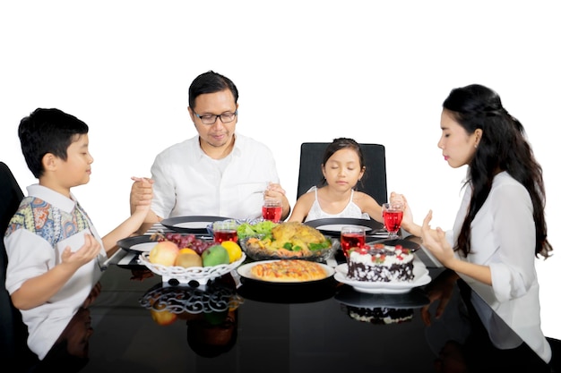 Famiglia asiatica che prega insieme prima di consumare i pasti