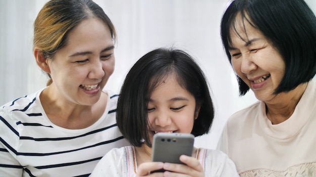 Famiglia asiatica felice che gioca insieme sullo smartphone, multi generazione di femmina asiatica