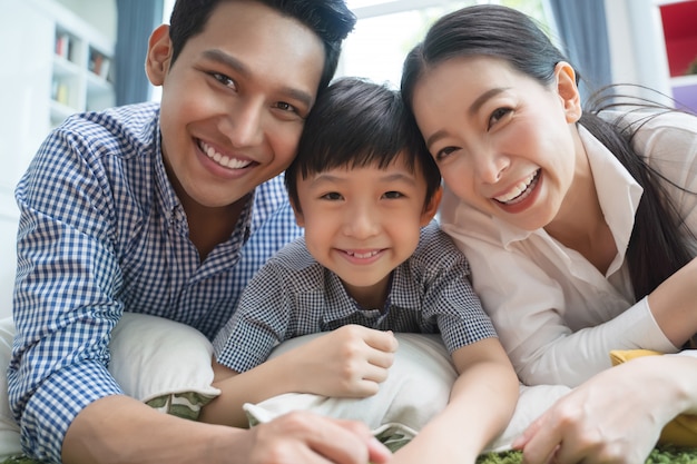 Famiglia asiatica felice che spende insieme tempo sul sofà in salone.