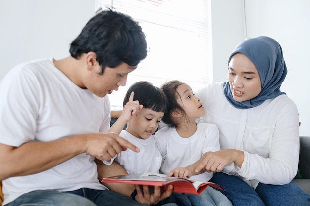 Famiglia asiatica felice che trascorre il tempo insieme a leggere un libro a casa