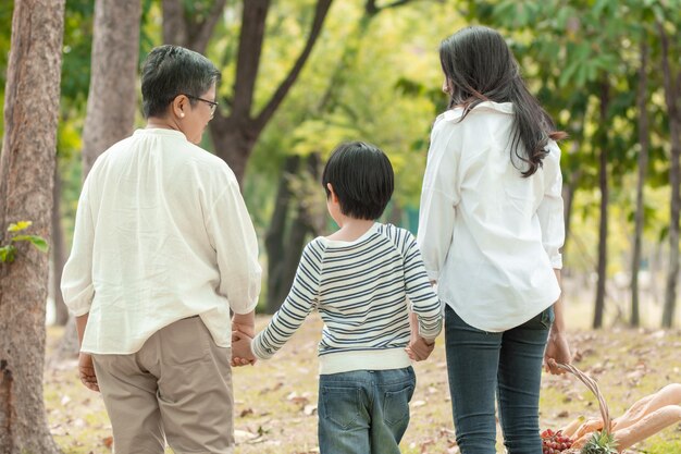 Famiglia asiatica felice che trascorre il tempo insieme all'aperto nella natura verde e nel parco vacanza del concetto dei genitori