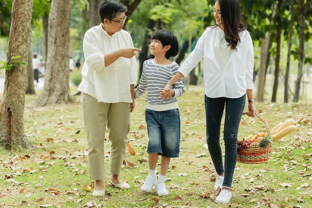 Famiglia asiatica felice che trascorre il tempo insieme all'aperto nella natura verde e nel parco vacanza del concetto dei genitori