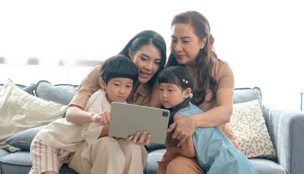 Famiglia asiatica felice che utilizza la tavoletta digitale nel vivere a casa rilassandosi a casa per il concetto di stile di vita