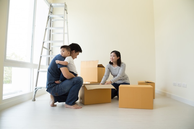 Famiglia asiatica felice con le scatole di cartone in nuova casa al giorno commovente