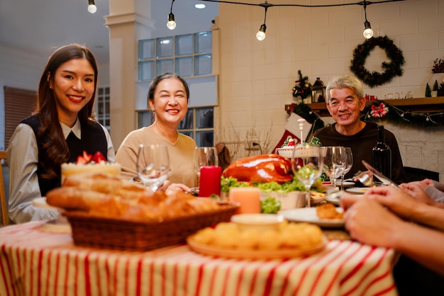 Famiglia asiatica felice e allegra che parla e sorride a casa per la cena di Natale Celebra la festa