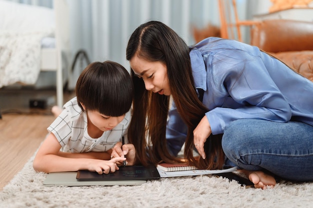 Famiglia asiatica unita a casa. Mamma insegna al bambino per l'educazione all'apprendimento online. Nuovo stile di vita normale.