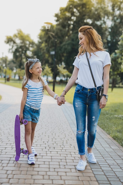 Famiglia attiva. Madre attiva e figlia che trascorrono del tempo nel parco mentre fanno un giro sullo skateboard